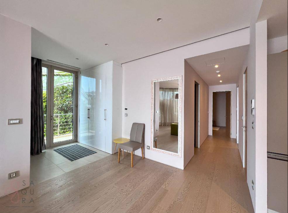 Heller Eingangsbereich mit Holzboden, großem Spiegel und Zugang zu einem Balkon.