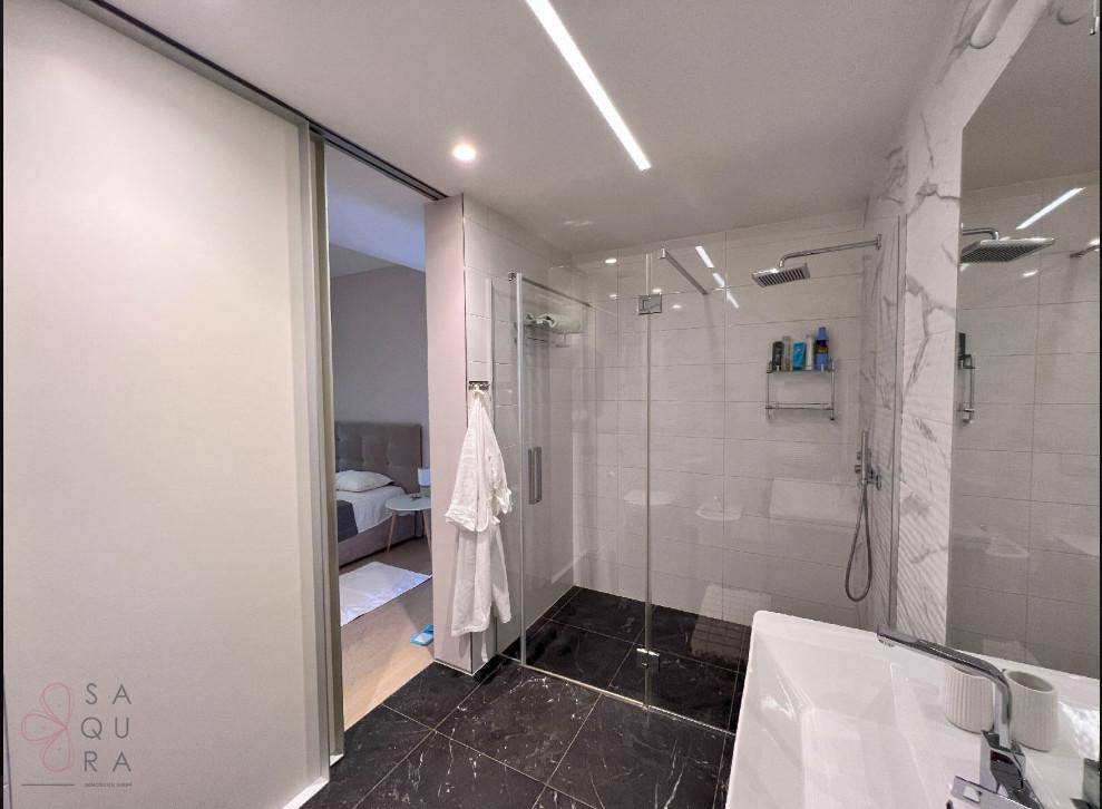 Modernes Badezimmer mit begehbarer Dusche und Schiebetür zum Schlafzimmer.