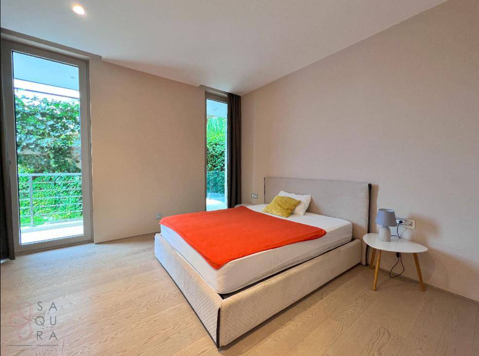 Helles Schlafzimmer mit Holzboden, großem Bett und Zugang zu einem kleinen Balkon.