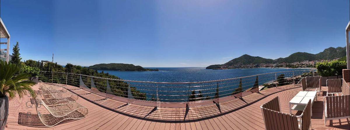 Exklusive Dachterrasse mit Liegestühlen und Essbereich, die einen spektakulären Panoramablick auf das Meer bietet.