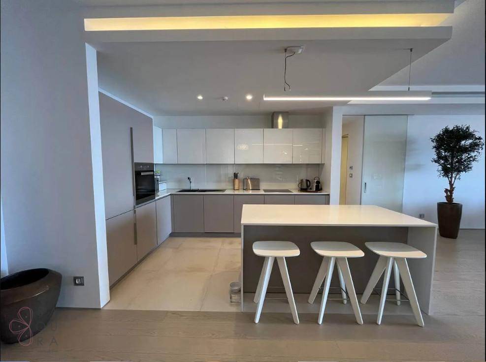 Moderne Einbauküche mit Kücheninsel, hellen Fronten und integrierten Geräten in minimalistischem Design.