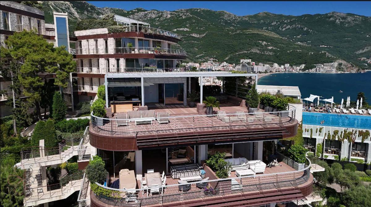 Luxuriöse Terrasse mit Ess- und Loungebereich, Meerblick und einem Pool im Hintergrund.