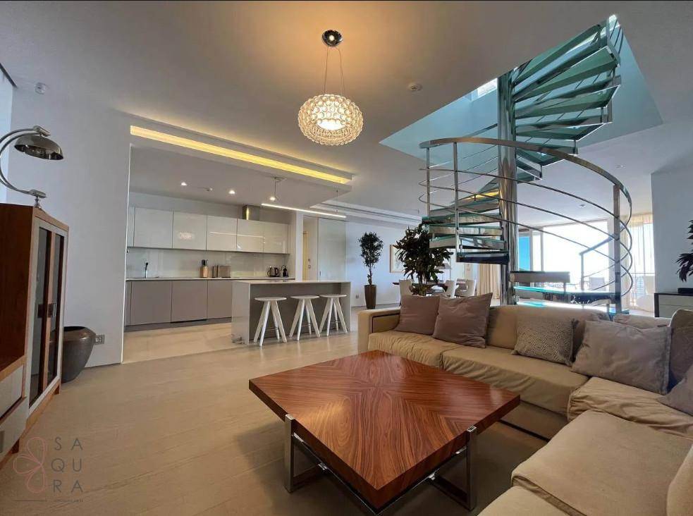 Gemütlicher Wohnbereich mit Sofa, Couchtisch und offener Küche, verbunden durch eine elegante Wendeltreppe.