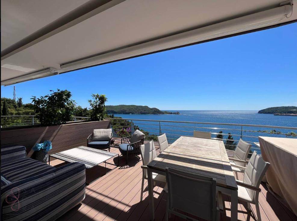 Große Terrasse mit Meerblick, Esstisch und bequemen Sitzgelegenheiten unter einer Markise.