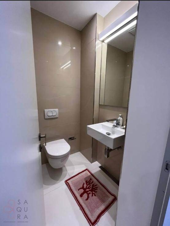 Kleines Gäste-WC mit Wand-WC, Waschbecken und beigen Fliesen.