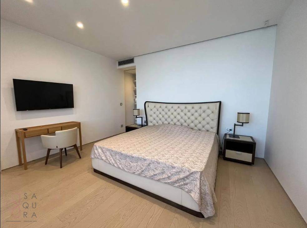 Elegantes Schlafzimmer mit gepolstertem Kopfteil, Schreibtisch und Wandfernseher.