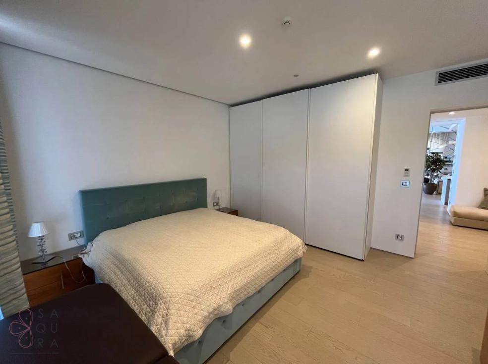 Modernes Schlafzimmer mit hellem Holzboden und großen weißen Einbauschränken.