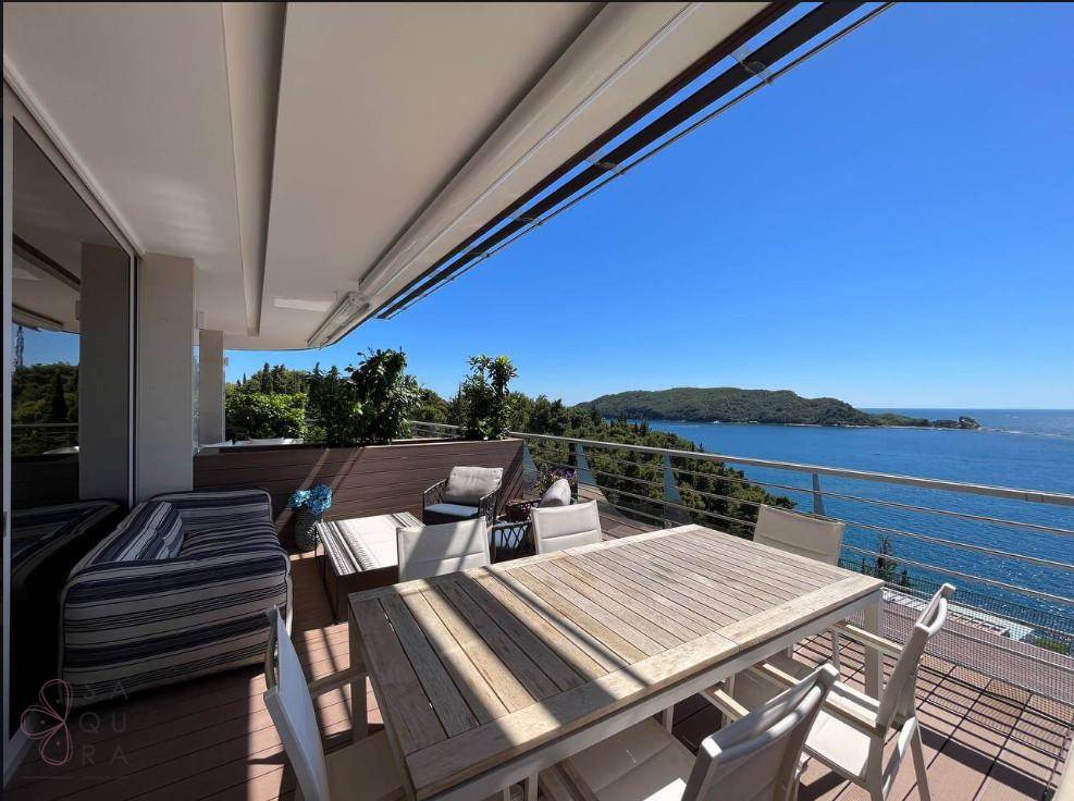 Elegante Terrasse mit Holzboden, Esstisch und atemberaubendem Blick auf das offene Meer.