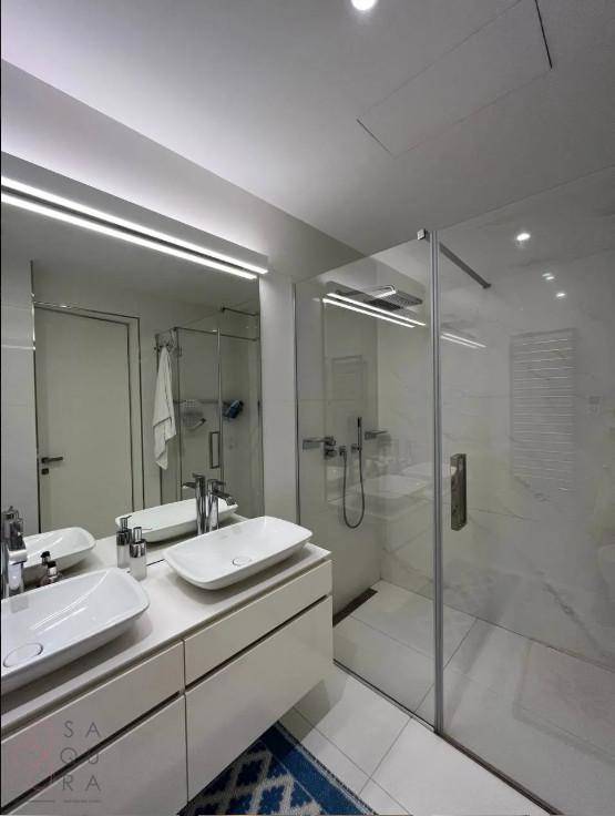 Helles Badezimmer mit Doppelwaschbecken, begehbarer Dusche und großem Spiegel.