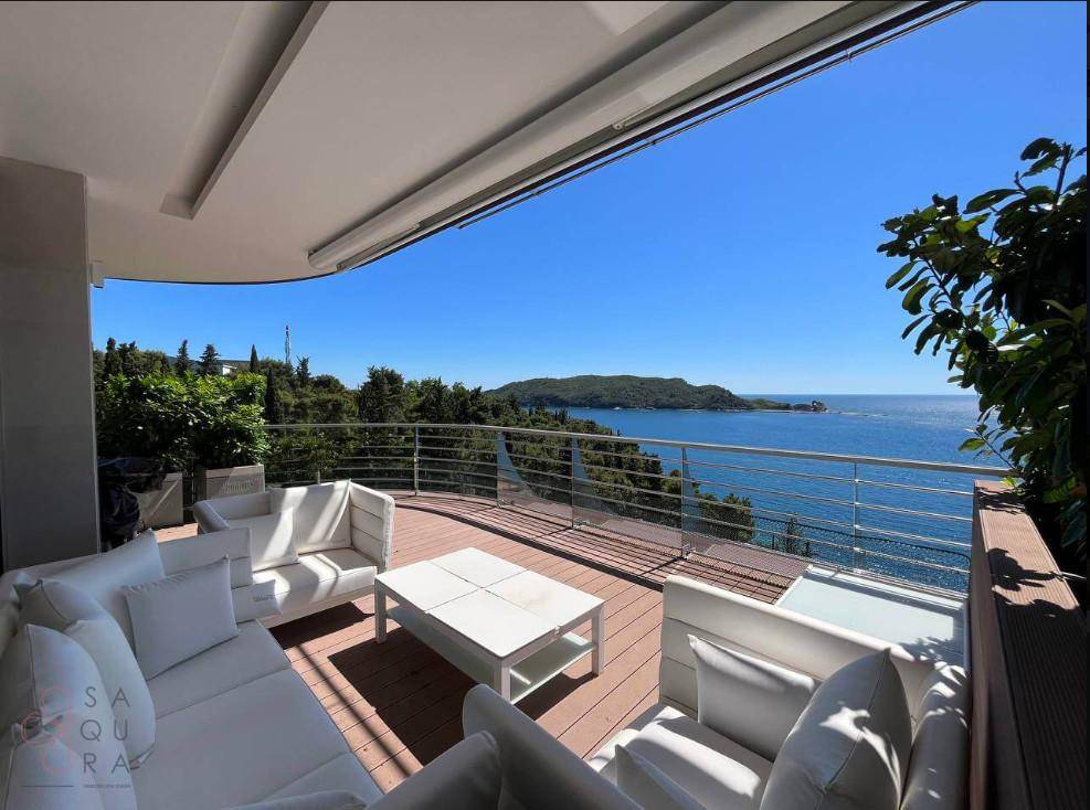 Stilvolle Terrasse mit weißen Sofas und weitem Blick auf das Meer und die grüne Landschaft.