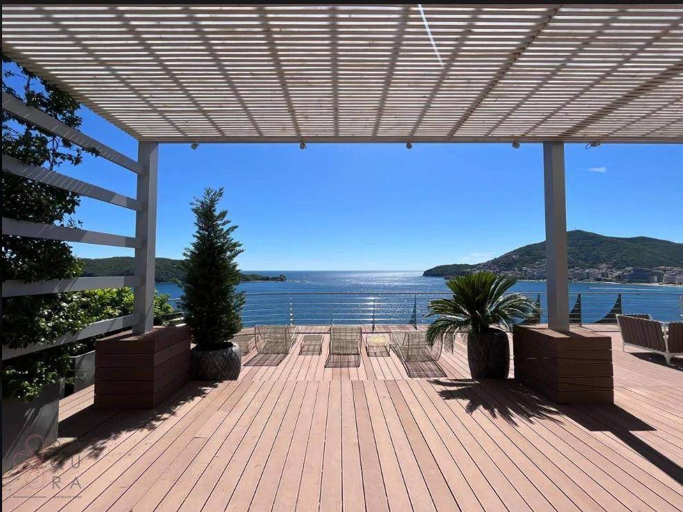 Weitläufige Terrasse mit atemberaubendem Meerblick, Liegestühlen und dekorativen Pflanzen unter einer Pergola.