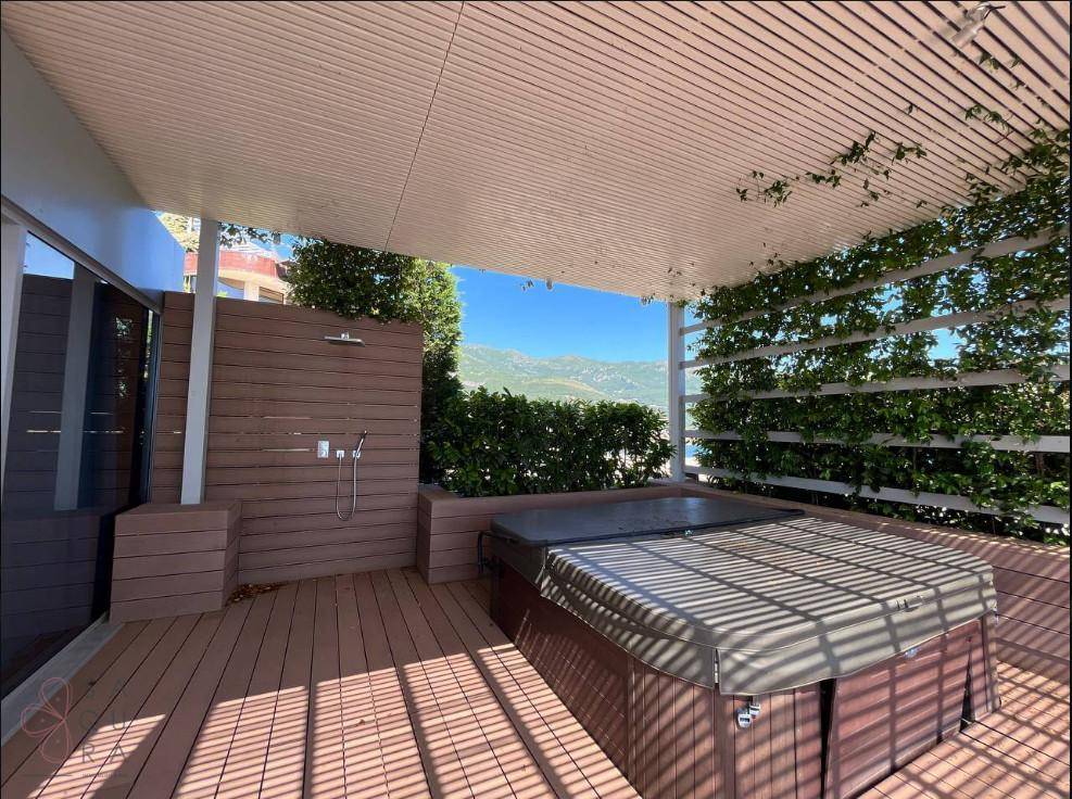 Entspannungsbereich auf der Terrasse mit Whirlpool, Außendusche und begrüntem Sichtschutz.