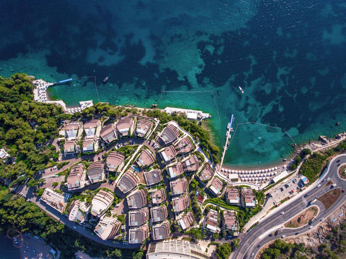 Weitläufige Luftaufnahme eines Küstenresorts mit vielen Gebäuden, Strand und Straße.