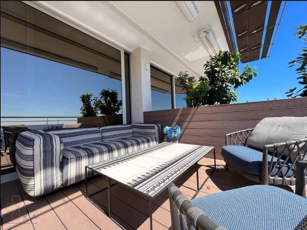 Moderne Terrasse mit bequemen Lounge-Möbeln und weitem Blick auf das blaue Meer.