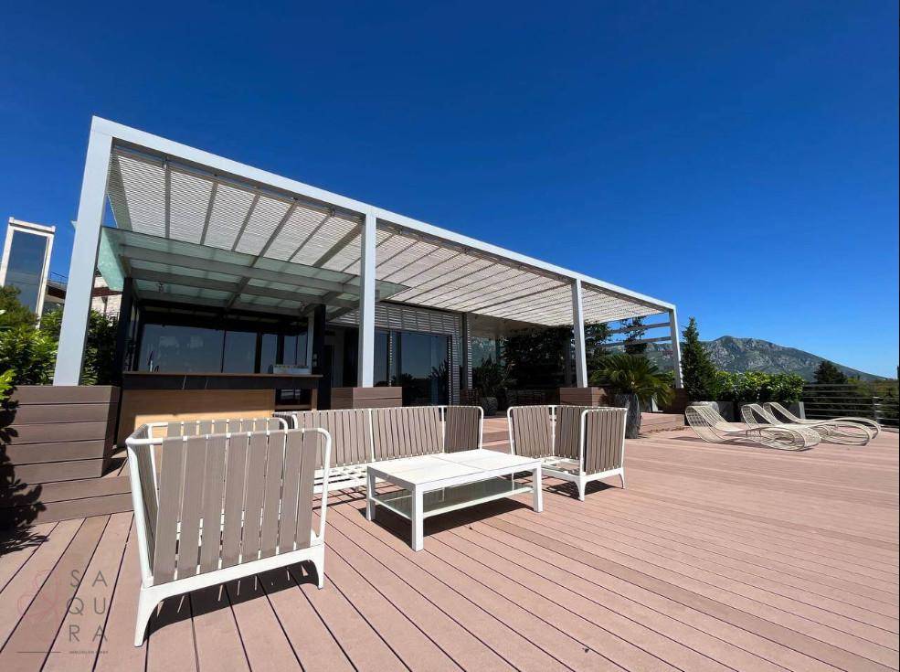 Geräumige Terrasse mit moderner Lounge-Möblierung, Pergola und weitem Blick auf die Berge.