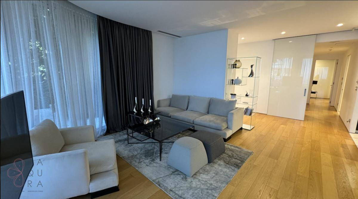 Helles Wohnzimmer mit bequemen Sofas, modernem Couchtisch und Holzboden, durch große Fenster lichtdurchflutet.