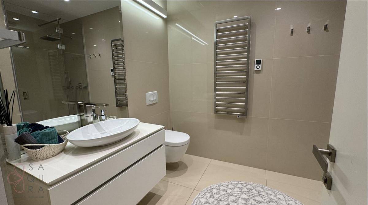 Elegantes Badezimmer mit modernem Waschbecken, Toilette und beheiztem Handtuchhalter.
