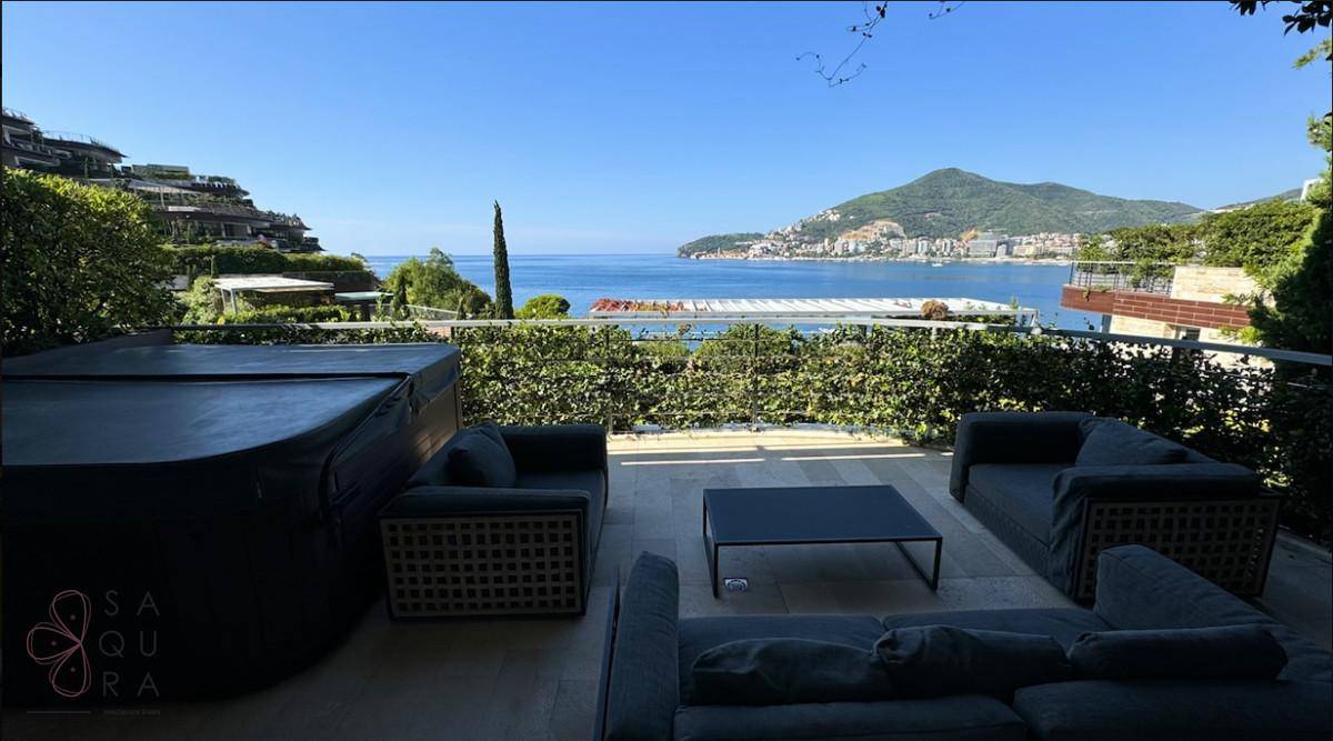 Luxuriöse Terrasse mit Whirlpool und bequemen Sitzgelegenheiten, mit atemberaubendem Meer- und Bergblick.