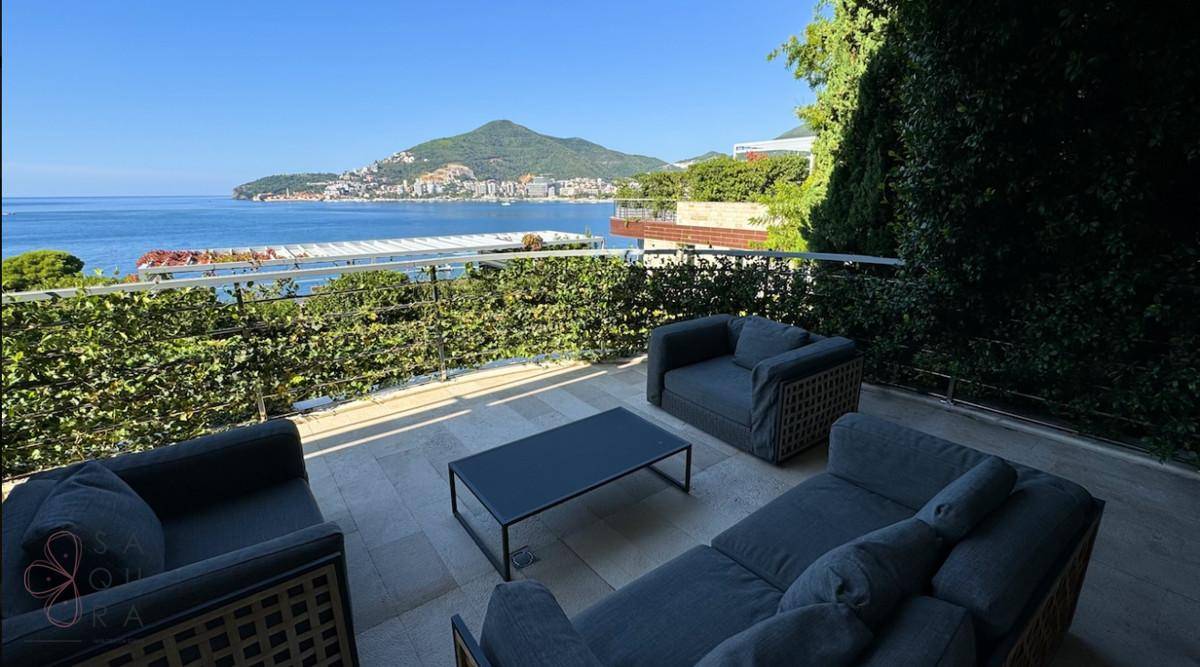 Helle Terrasse mit moderner Sitzgruppe und spektakulärem Blick auf das Meer und die Berge.