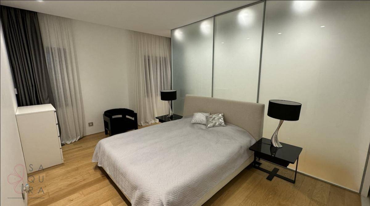 Modernes Schlafzimmer mit Doppelbett, Nachttischen und stilvollen Lampen, durch Glaswände abgetrennt.