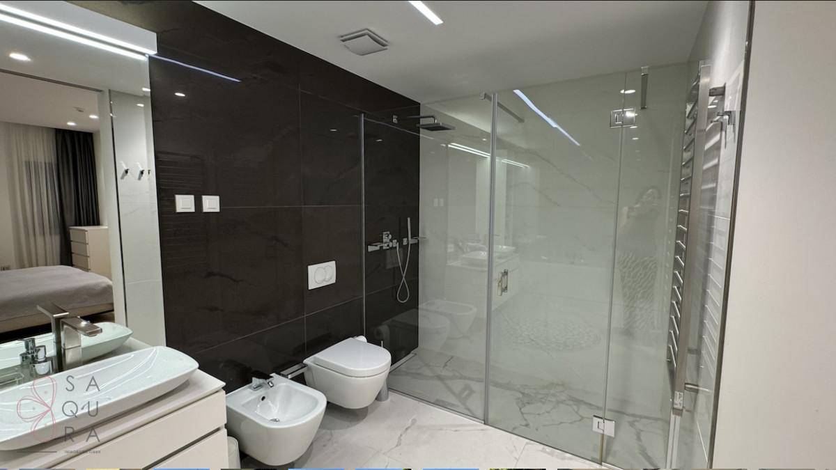 Modernes Badezimmer mit begehbarer Dusche, Bidet und eleganten dunklen Fliesen.