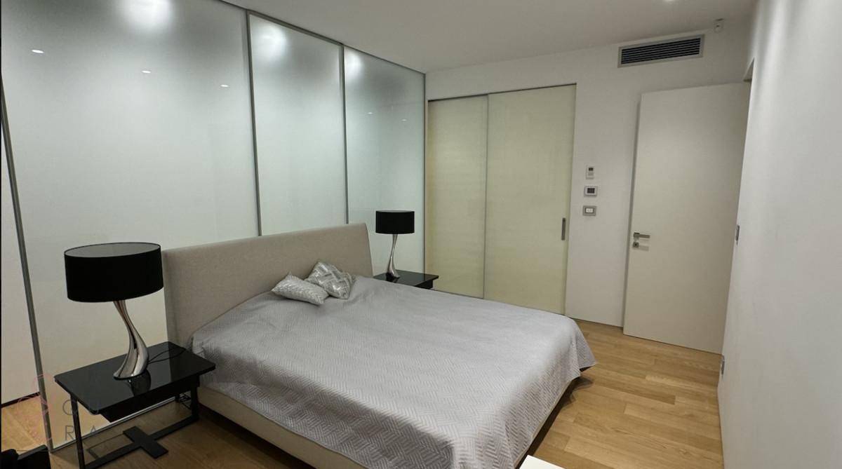 Elegantes Schlafzimmer mit Doppelbett und integrierter Schiebetür in der modernen Glaswand.