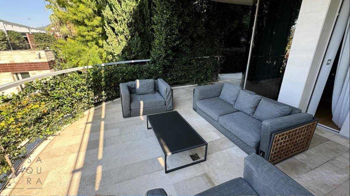 Geräumige Terrasse mit modernen Outdoor-Möbeln, umgeben von üppigem Grün.