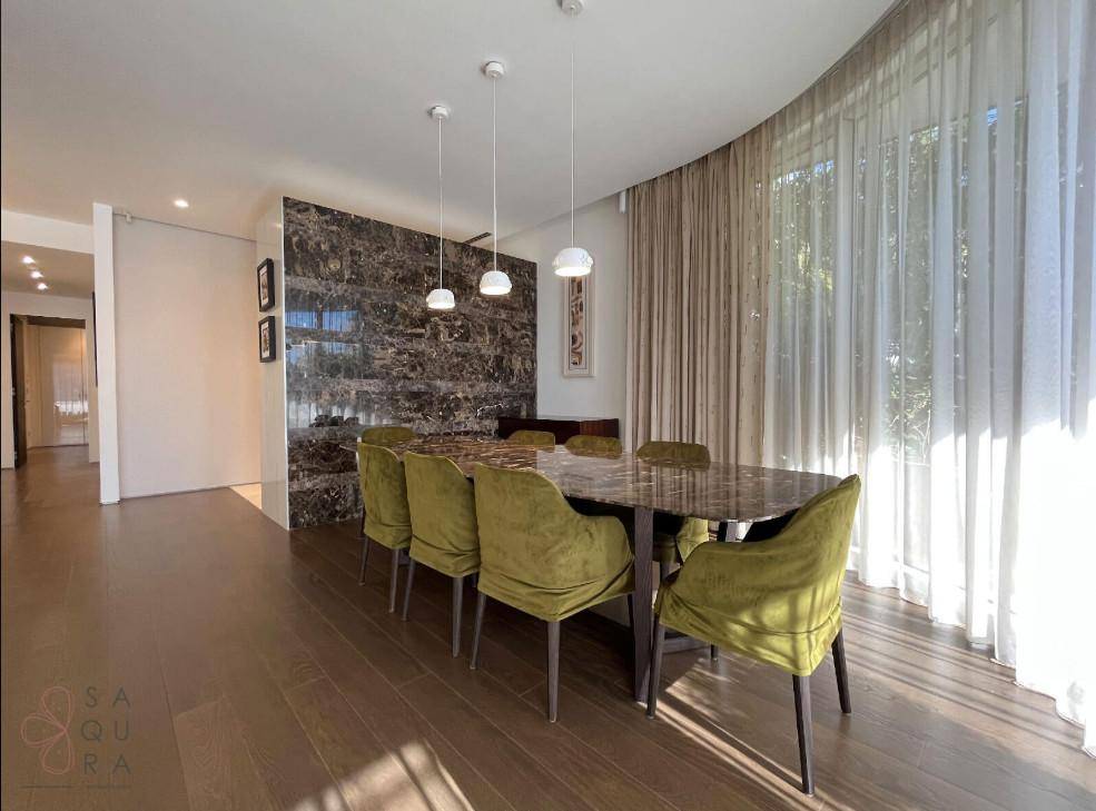 Eleganter Essbereich mit Marmorwand, Holzboden und großen Fenstern für viel Tageslicht.