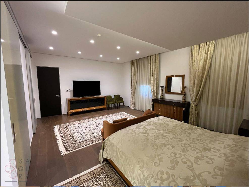 Geräumiges Hauptschlafzimmer mit großem Fernseher, Kommode und eleganten Vorhängen, die für Privatsphäre sorgen.