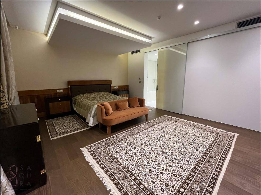Komfortables Hauptschlafzimmer mit großem Bett, stilvollem orangefarbenem Sofa und zwei eleganten Teppichen.