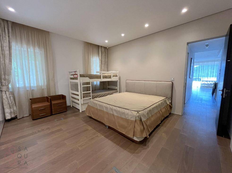 Helles Schlafzimmer mit Doppelbett und Etagenbett, ausgestattet mit Nachttischen und Holzboden.