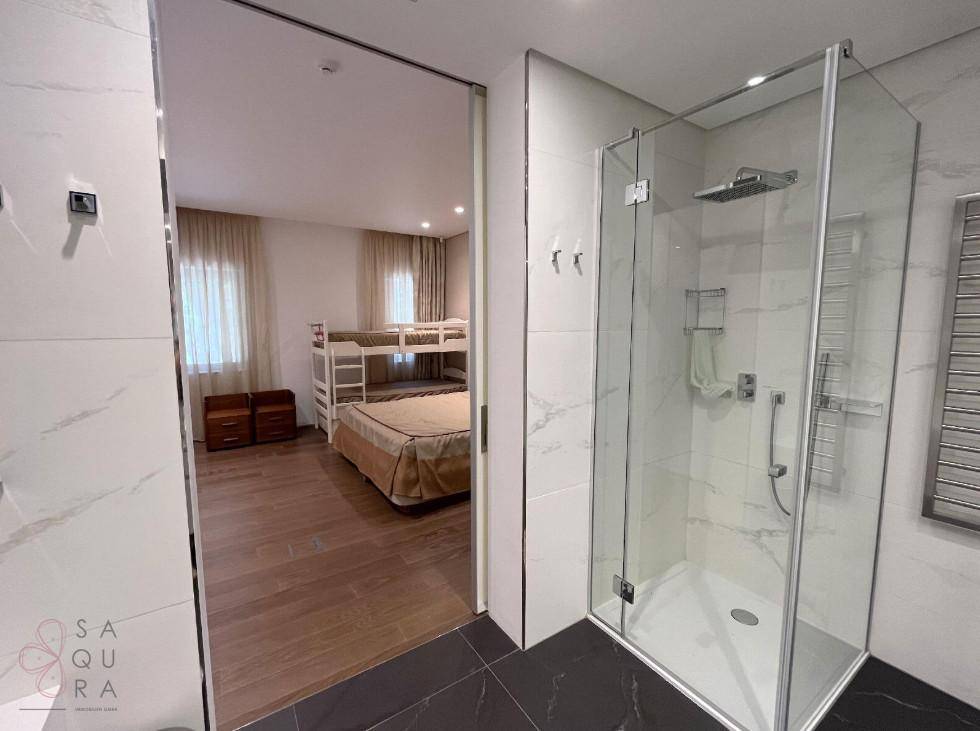 Modernes Badezimmer mit begehbarer Dusche, eleganten Marmorfliesen und Blick in das angrenzende Schlafzimmer.