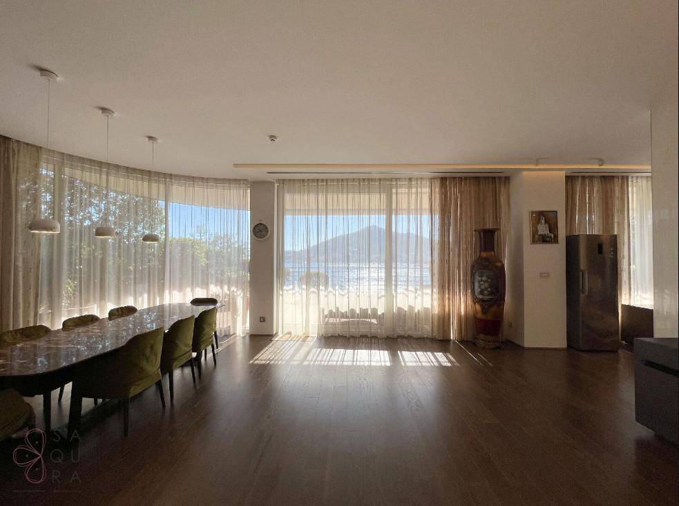 Heller Essbereich mit großen Fenstern, Holzboden und weitem Blick auf Meer und Berge.
