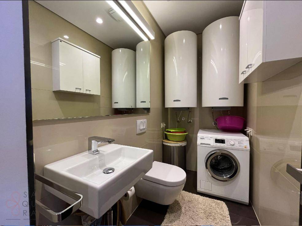 Praktischer Hauswirtschaftsraum mit Waschbecken, WC, Waschmaschine und Warmwasserbereitern für den täglichen Gebrauch.