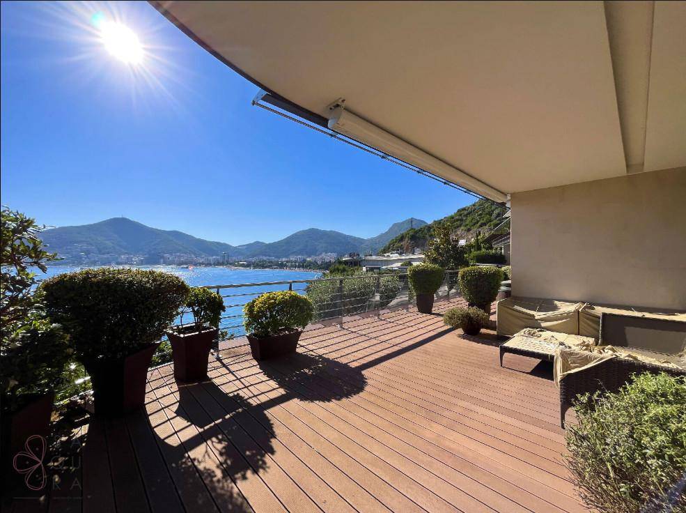 Weitläufige Terrasse mit Holzdeck und Sitzgelegenheiten, die einen weiten Blick auf das Meer und die Berge bietet.