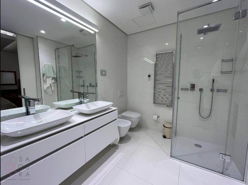 Geräumiges Badezimmer mit Doppelwaschbecken, wandhängendem WC, Bidet und großer begehbarer Dusche.