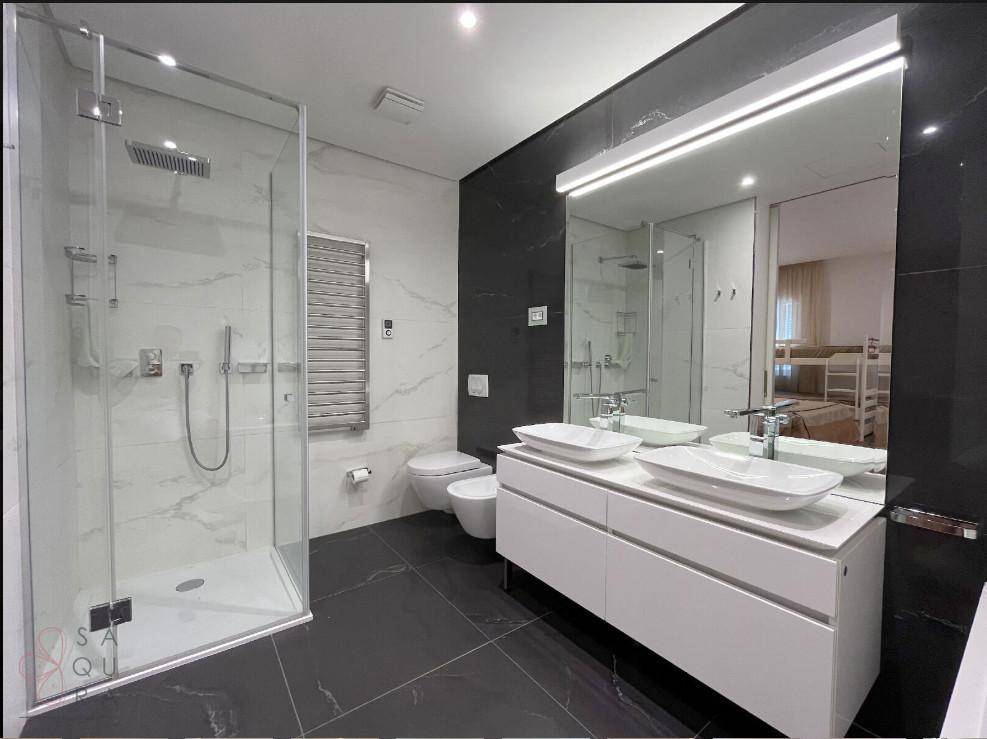 Luxuriöses Badezimmer mit Doppelwaschbecken, wandhängendem WC und geräumiger begehbarer Dusche.