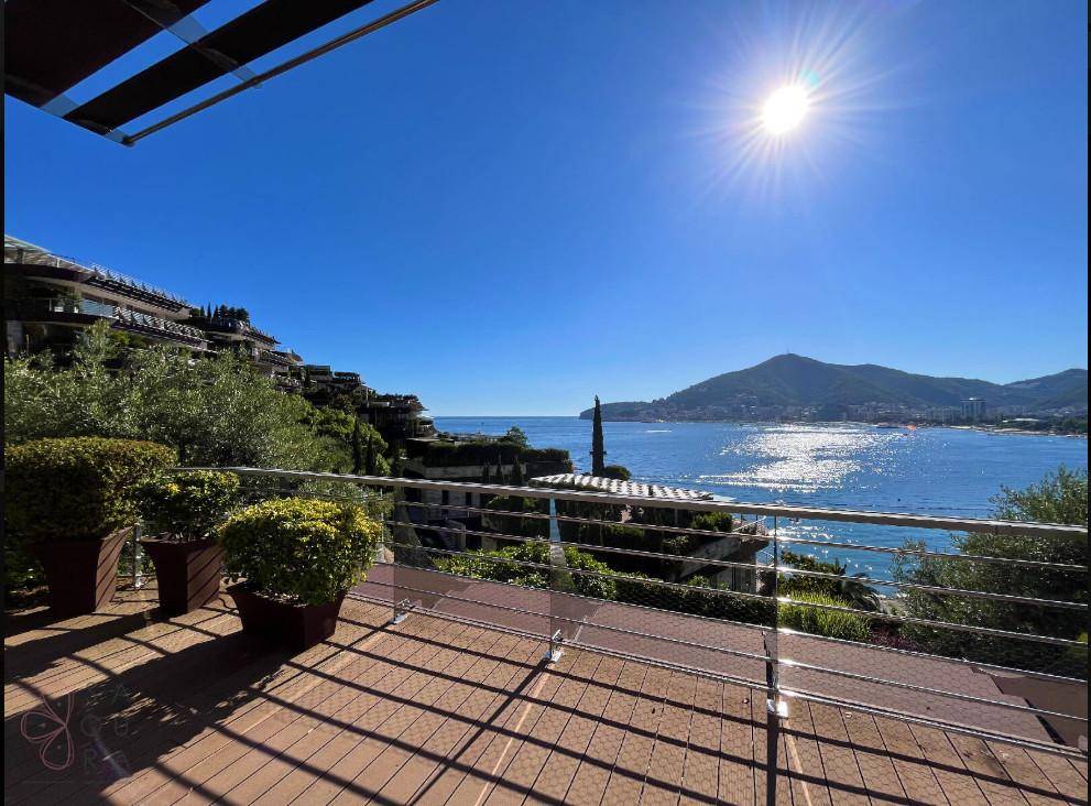 Große Sonnenterrasse mit Holzdeck, Meerblick und strahlendem Sonnenschein über der Küste.