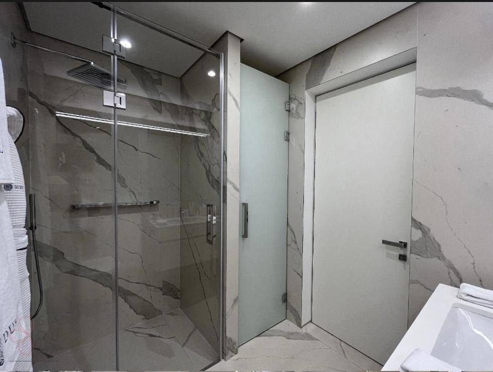 Modernes Badezimmer mit geräumiger begehbarer Dusche und Milchglastür.
