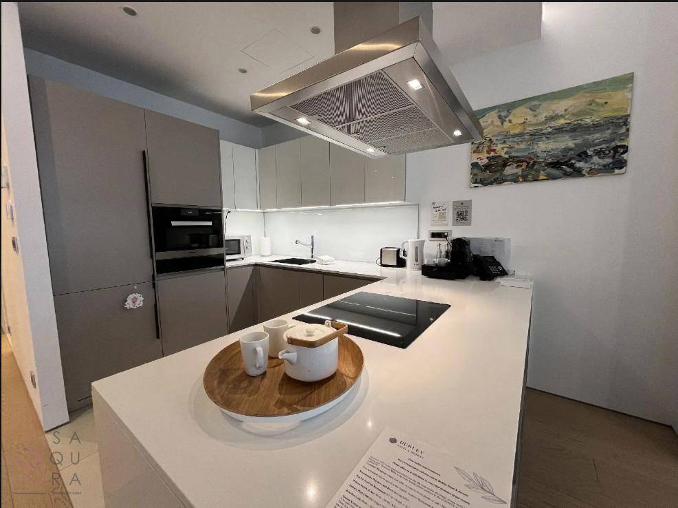 Moderne Küche mit Kücheninsel, integrierten Geräten und heller Arbeitsplatte, ideal für kulinarische Erlebnisse.