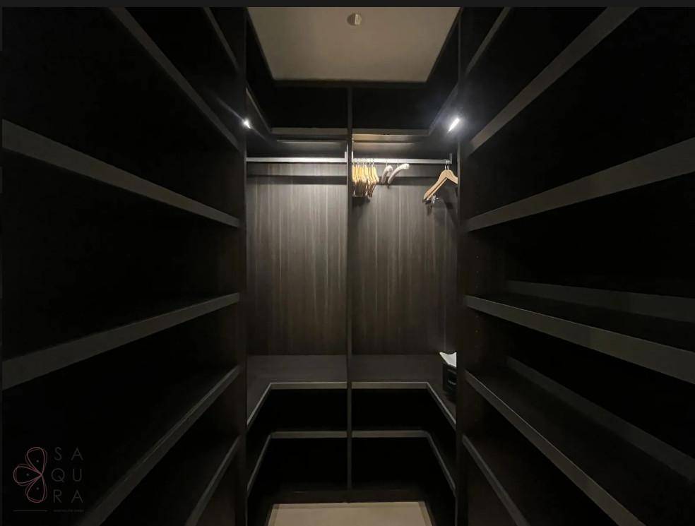 Geräumiger begehbarer Kleiderschrank mit dunklen Regalen und viel Stauraum.