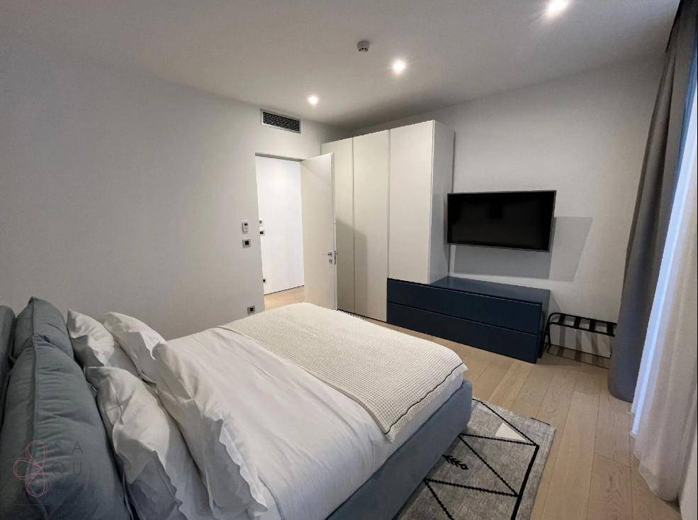 Schlafzimmer mit großem Kleiderschrank, Fernseher und modernem Bett.