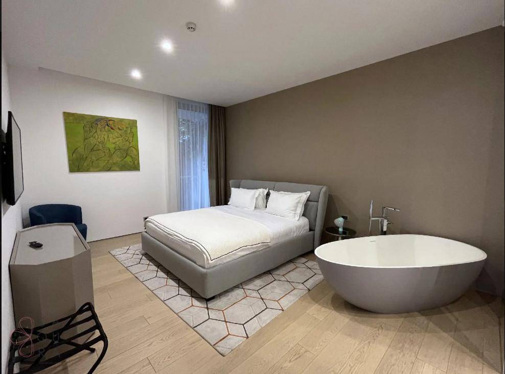 Modernes Schlafzimmer mit freistehender Badewanne, Holzboden und dezenter Wandgestaltung.