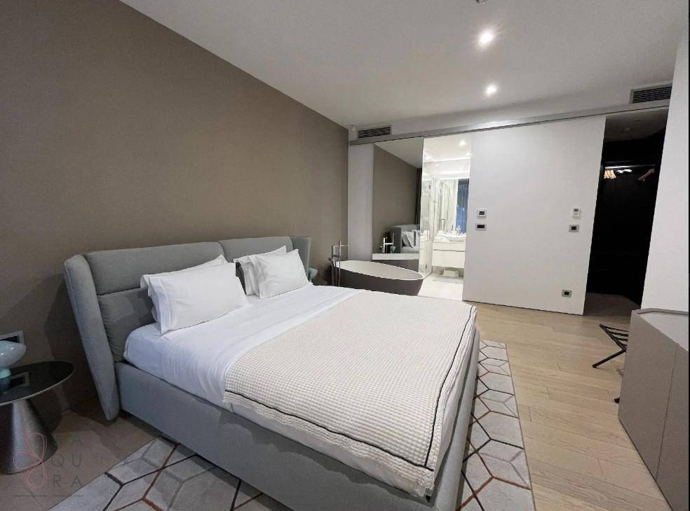 Schlafzimmer mit großem Bett und direktem Zugang zu einem luxuriösen Badezimmer mit Badewanne.