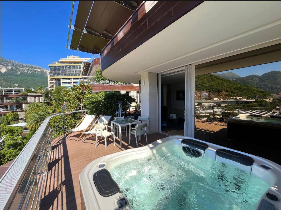 Geräumige Terrasse mit Whirlpool, Essbereich und weitem Blick über die Stadt und das Meer.