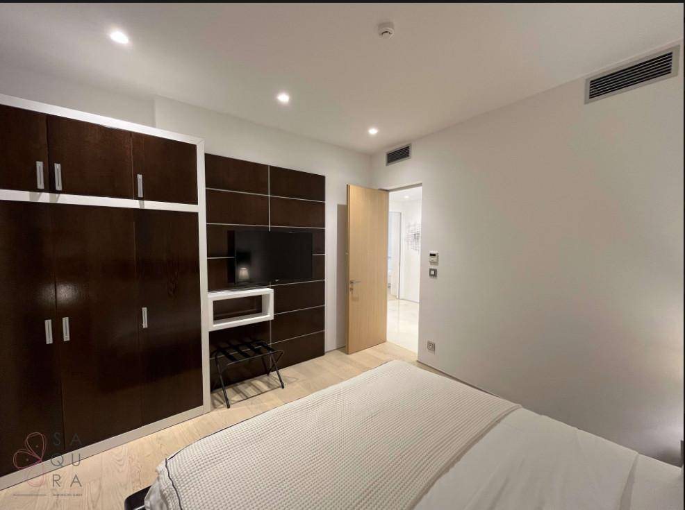 Geräumiges Schlafzimmer mit Einbauschränken, Fernseher und Zugang zu einem weiteren Raum.