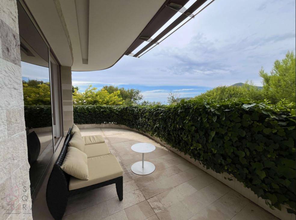 Sonniger Terrassenbereich mit Loungemöbeln und weitem Blick auf das Meer und die Berge.
