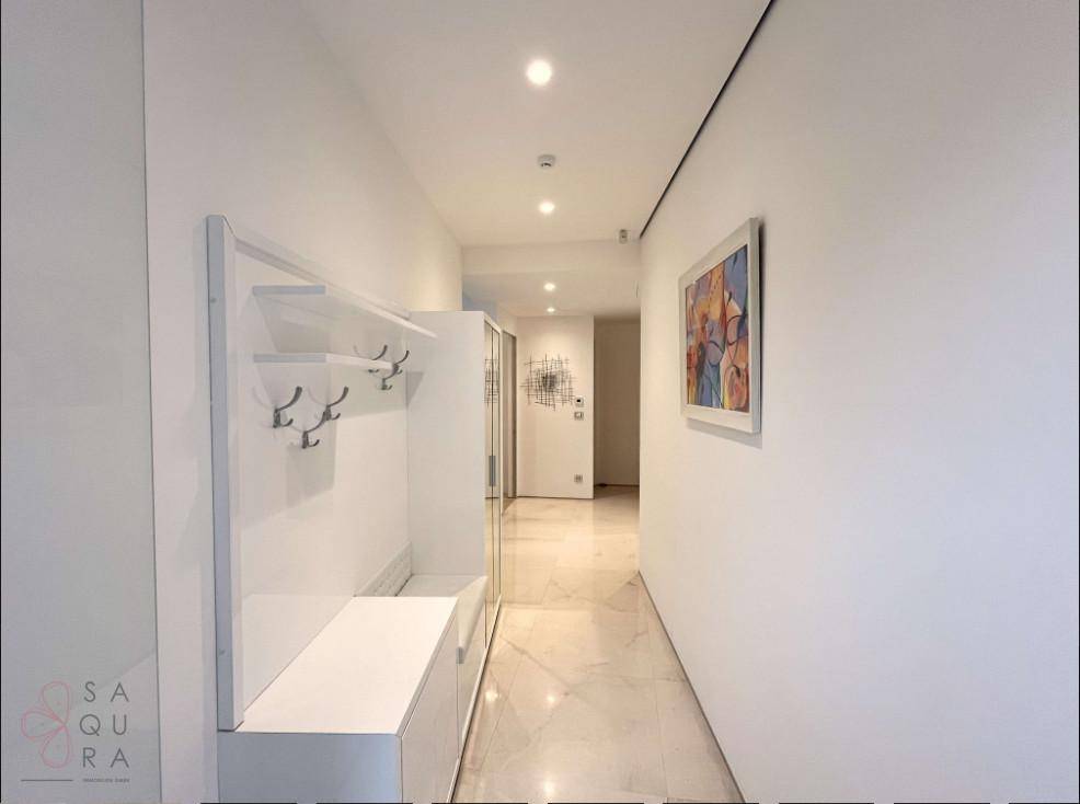 Moderner Flur mit weißer Garderobe, Sitzbank und farbenfrohem Kunstwerk an der Wand.