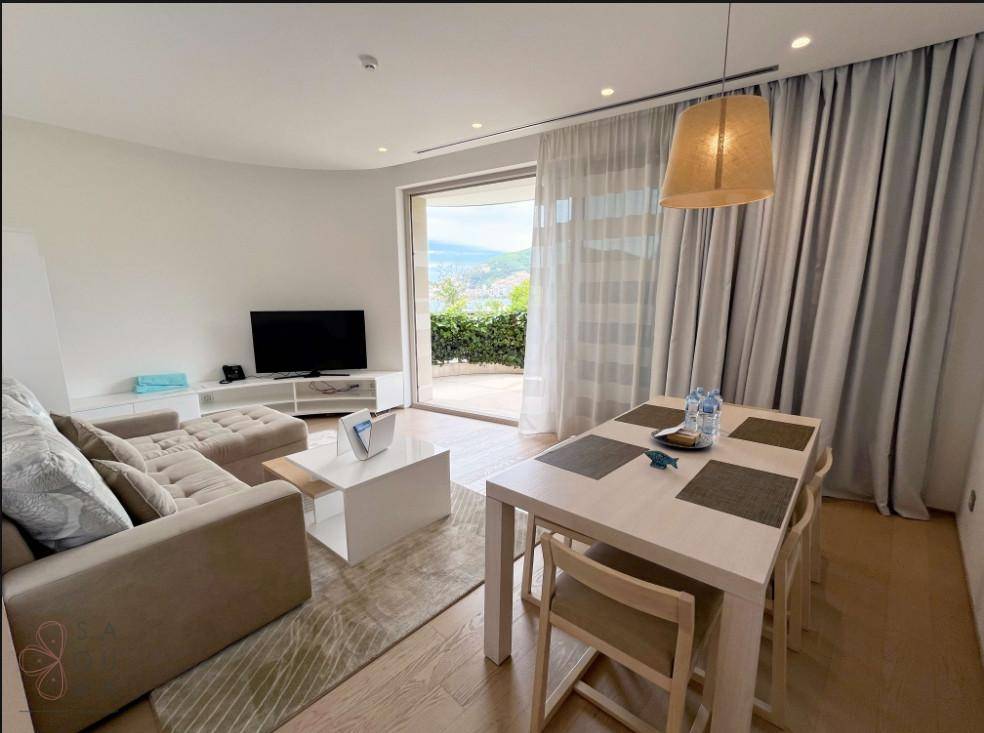 Heller Wohn-Essbereich mit Esstisch, Sofa und großem Fenster mit Blick ins Grüne.