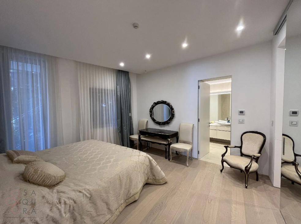 Elegantes Schlafzimmer mit großem Bett, Fenster und Zugang zum modernen Badezimmer.